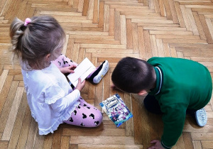 2 dzieci układa bajkowy obrazek z pociętych elementów.